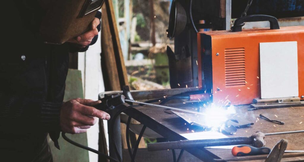 Man welding old shovel, close up.